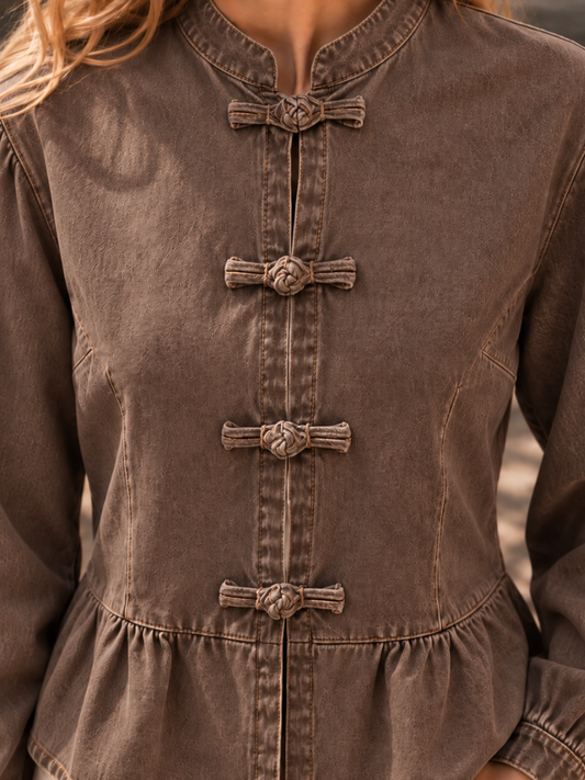 woman in ireland wearing a brown long-sleeve top with a mandarin collar and decorative knotted front buttons.